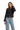 A woman wearing a black tweed jacket with gold chain accents and gold buttons, paired with blue jeans.