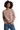A woman wearing a dusty rose fleece set consisting of a sweatshirt and pants, standing with one hand in a pocket.