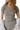 A person wearing a heather grey pointelle baby tee with short sleeves and white pearl necklaces.