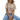 A woman sitting on a platform wearing a camel and white striped tee with a semi cropped, slightly boxy fit.