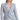 A woman wearing a mixed blue tweed blazer with frayed detailing and light gold buttons, paired with white trousers.