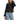 A woman wearing a black tweed jacket with gold chain accents and gold buttons, paired with blue jeans.